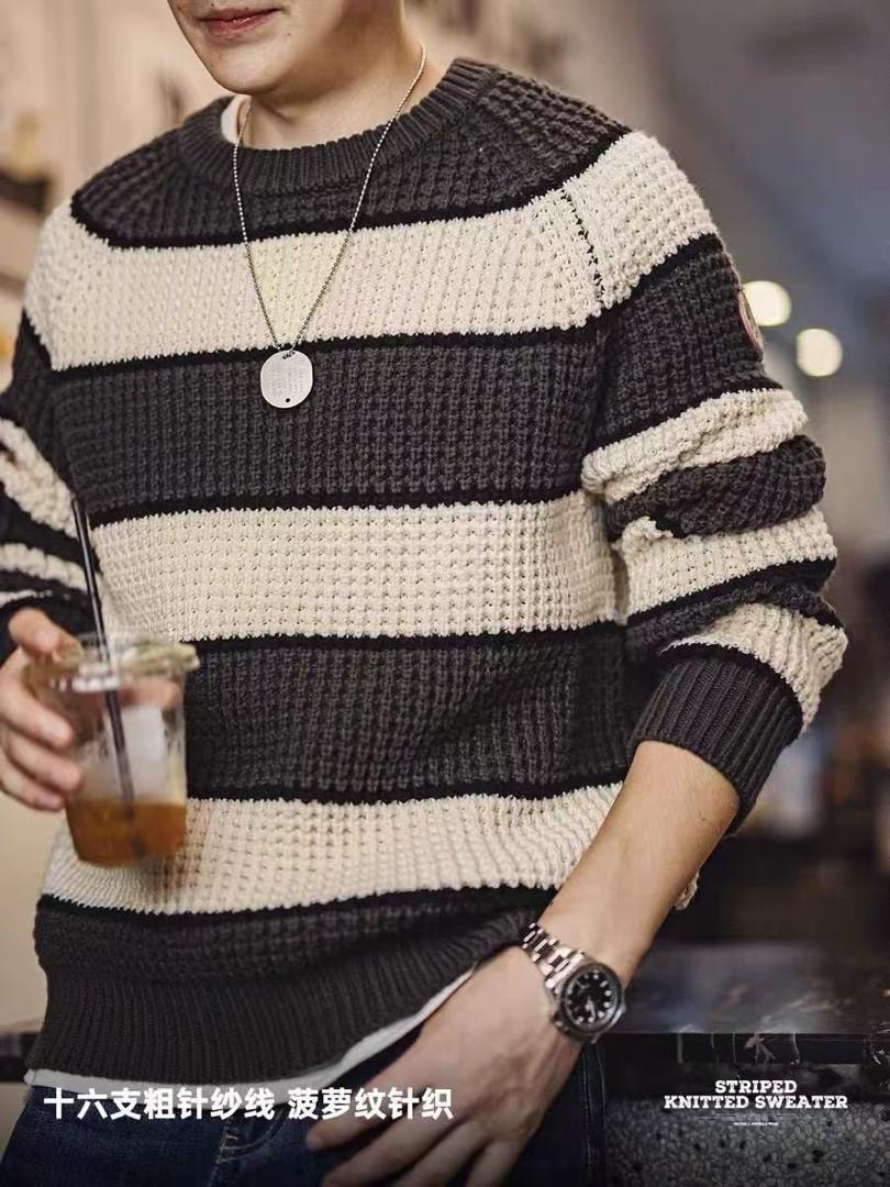 Man wearing gray striped knitted sweater with necklace and watch.