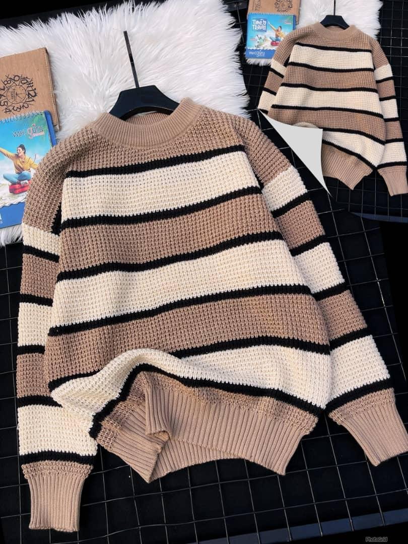 Brown striped knitted sweater with textured panels on black grid with white fur.