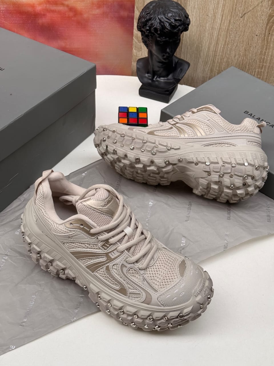 Beige Balenciaga studded track sneakers with brand boxes and accessories.
