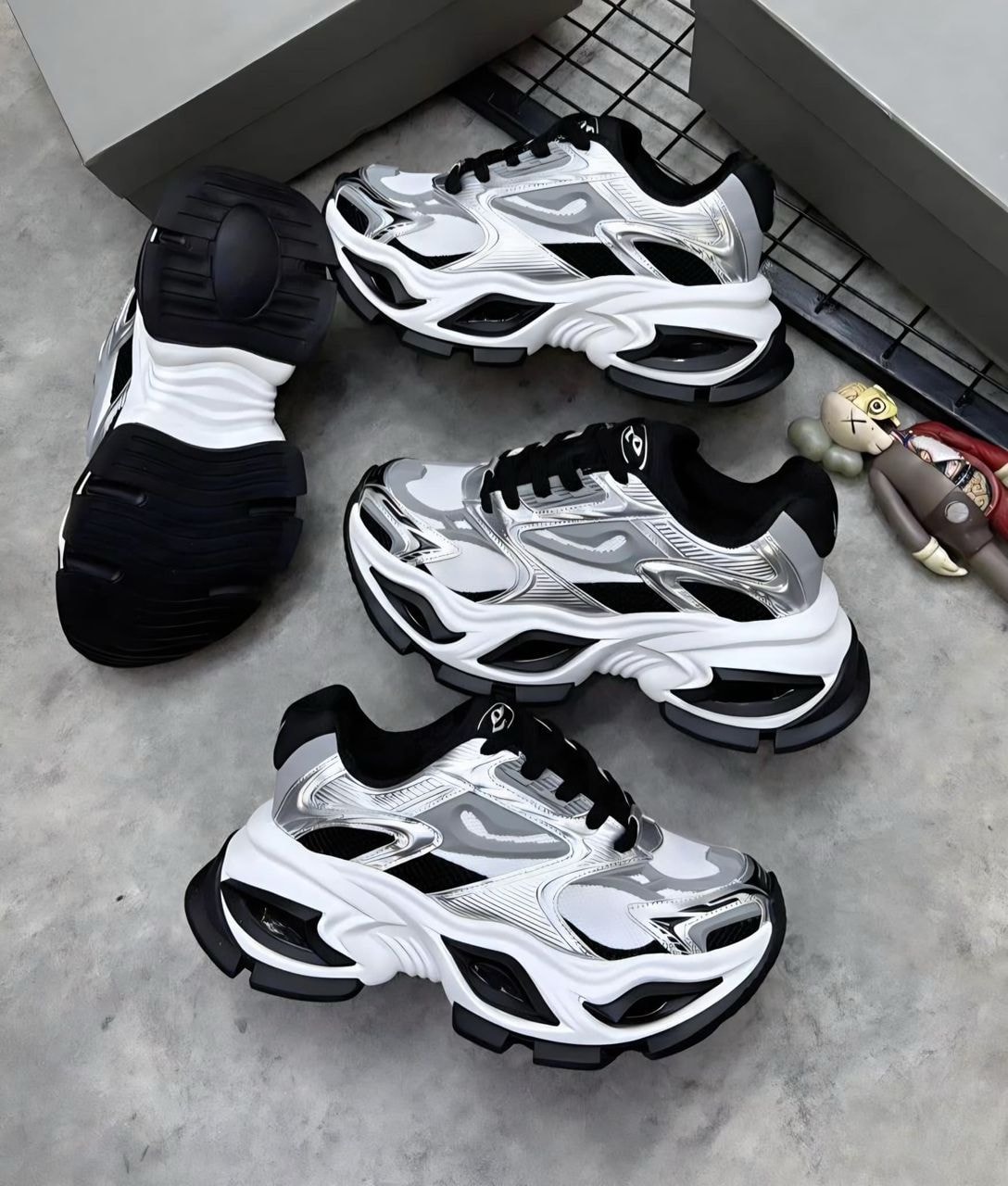 White black and silver chunky sneakers shown in multiple angles on concrete.