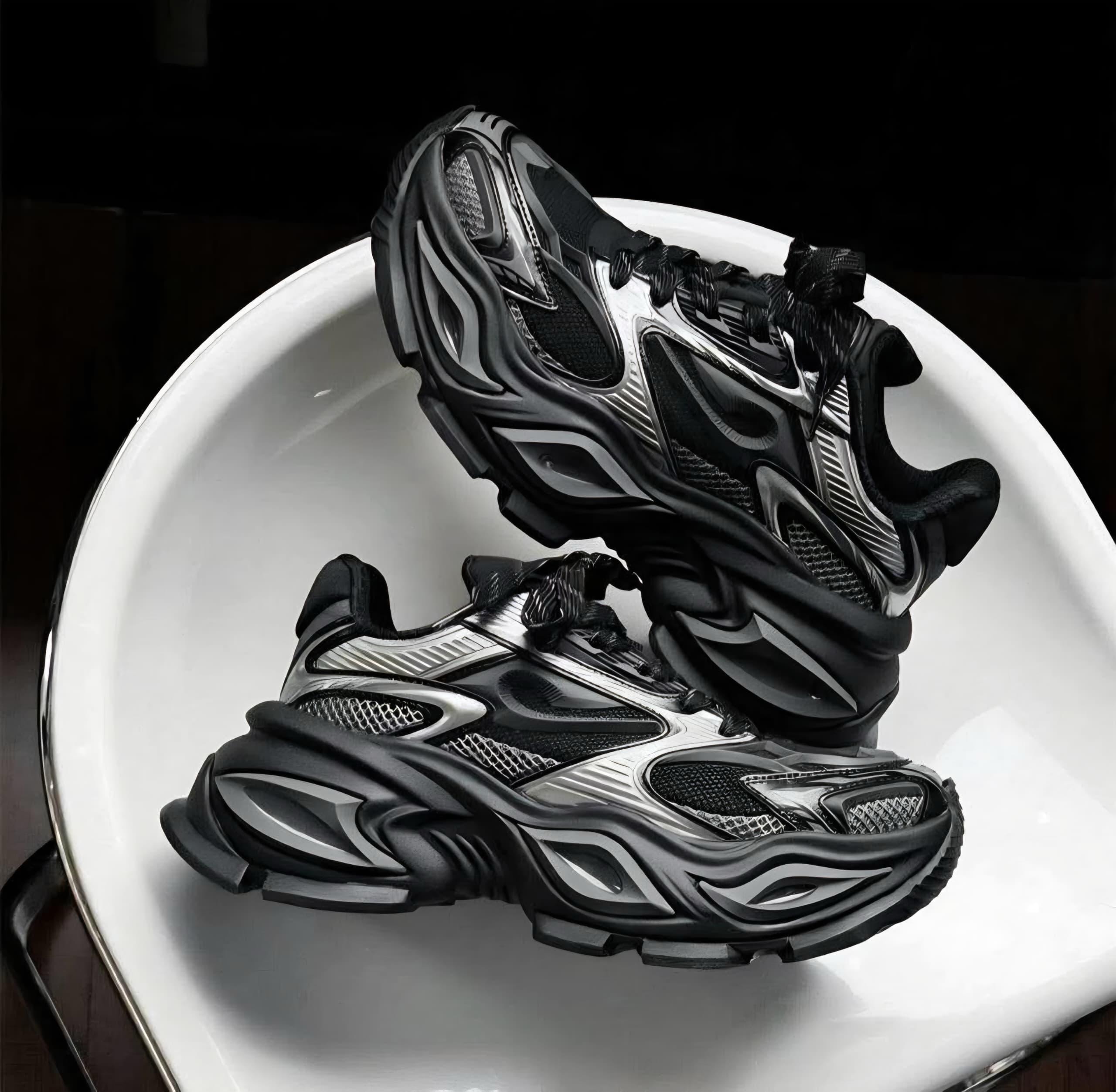 Black and silver chunky sneakers in dramatic lighting on white surface.