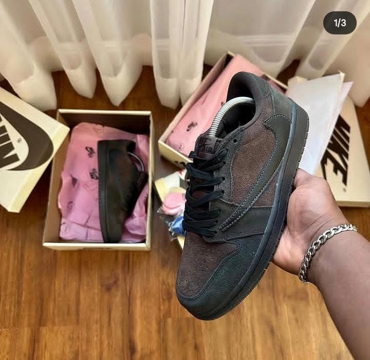 Dark brown suede Nike SB Dunk Low Pro held in hand with boxes.