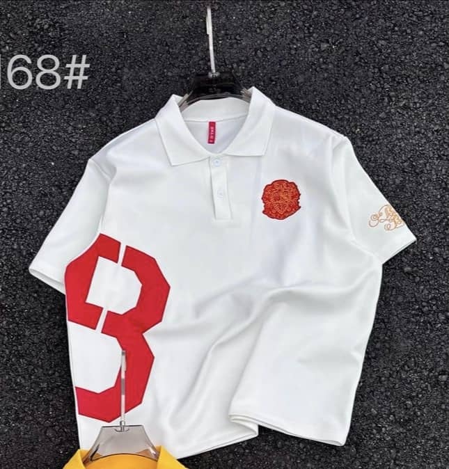 White polo shirt with large red number graphic, red chest emblem and gold sleeve embroidery.