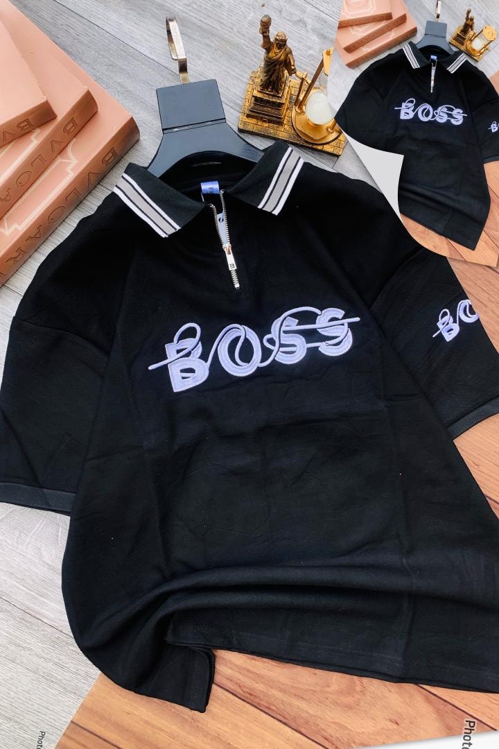 Black zip polo shirt with BOSS embroidery on styled surface with decor.