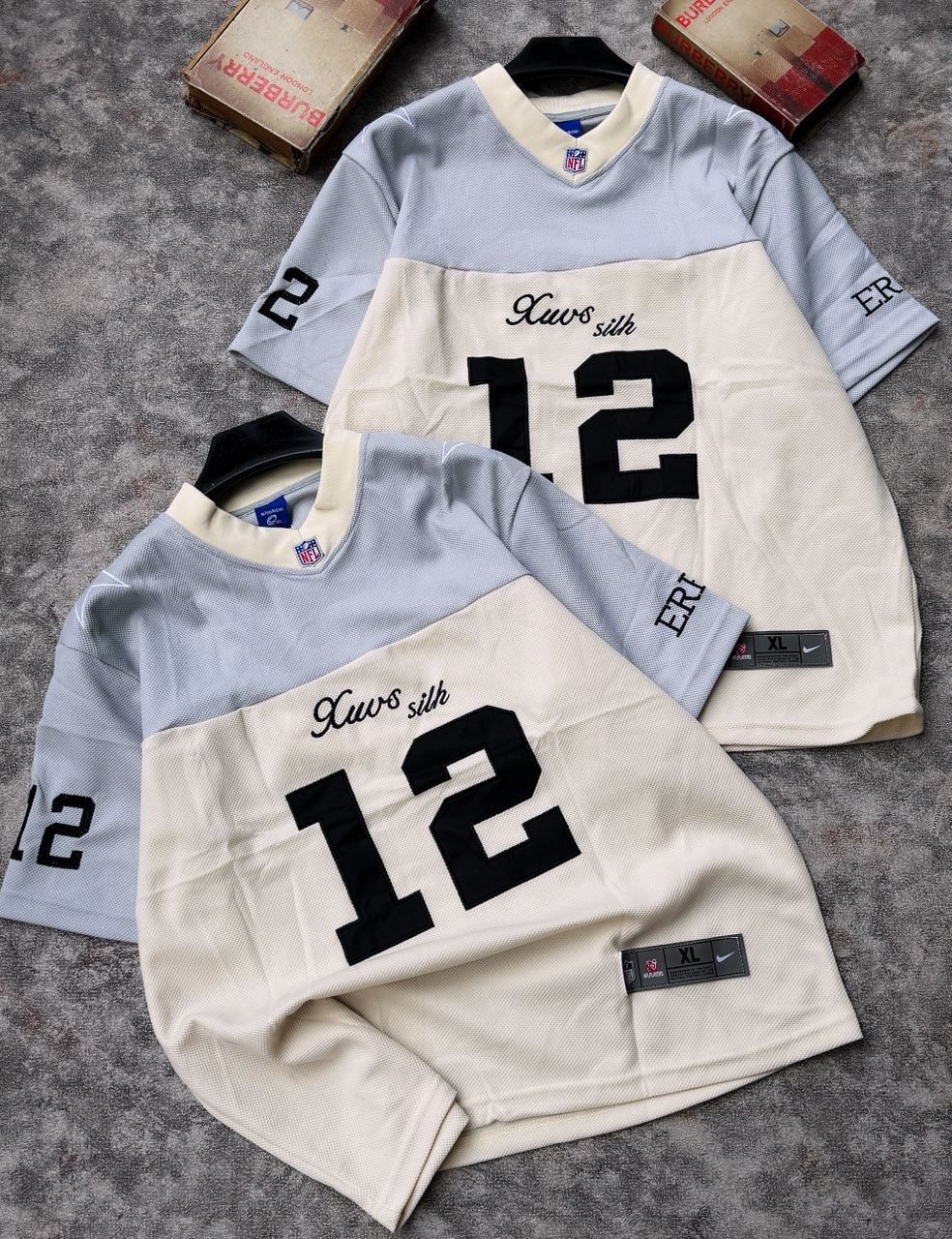 Two number 12 mesh jerseys in gray and cream colorways laid flat.