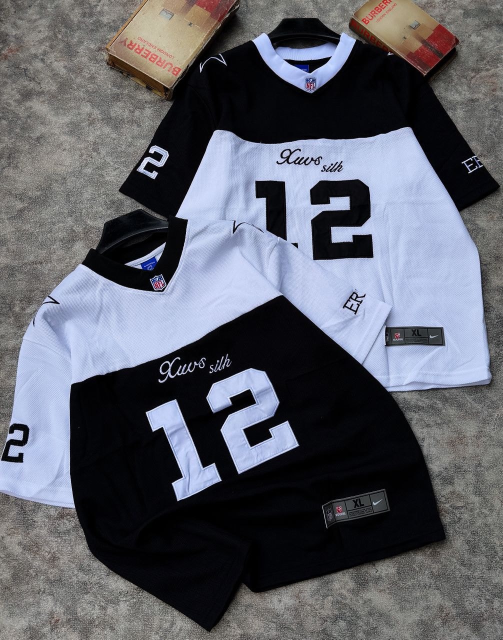 Two number 12 mesh jerseys in black and white colorways laid flat on surface.