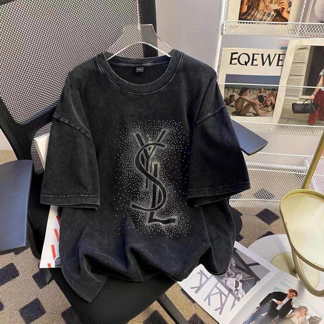 Dark washed t-shirt with sparkling YSL rhinestone logo, displayed on a chair.