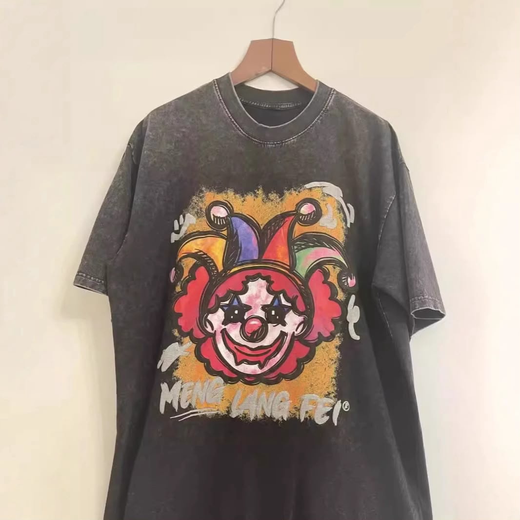 Dark washed t-shirt with colorful clown face graphic, hanging on a wooden hanger.
