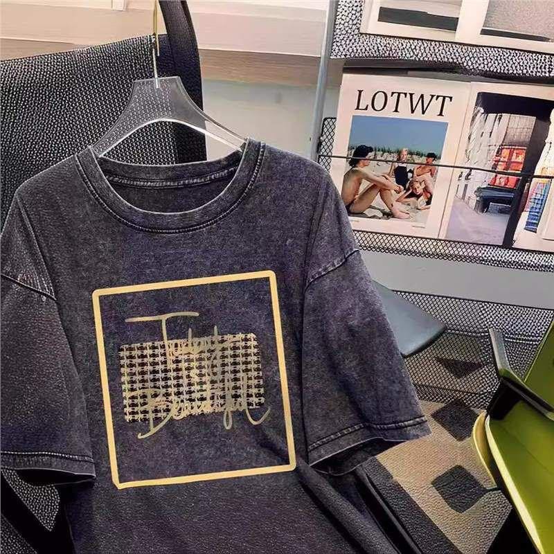 Dark washed t-shirt with gold square graphic print, hanging on a transparent hanger.