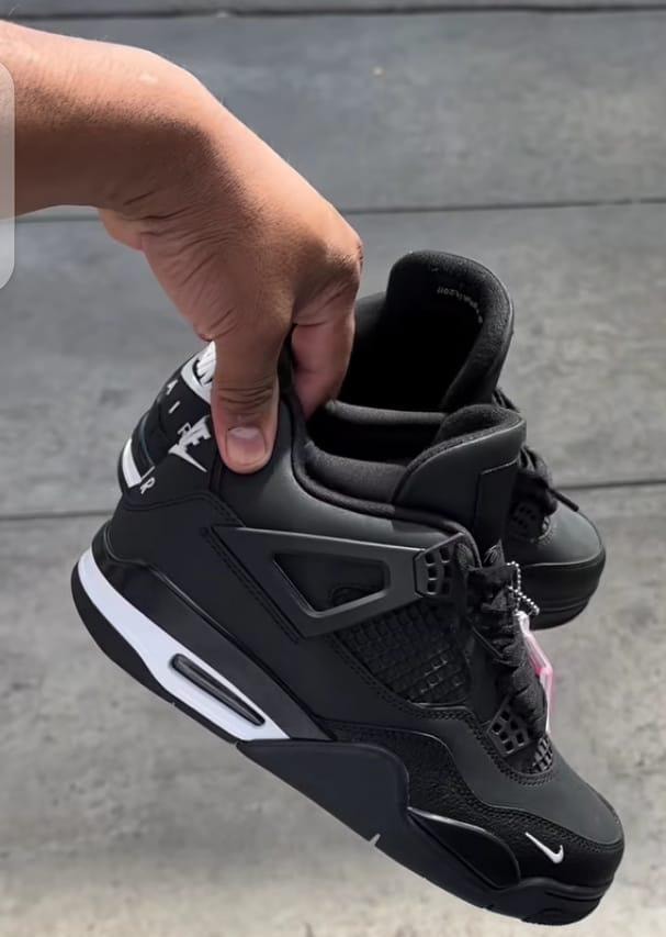 Hand holding Nike Air Jordan 4 Black Cat sneaker to show side profile, interior, and details.