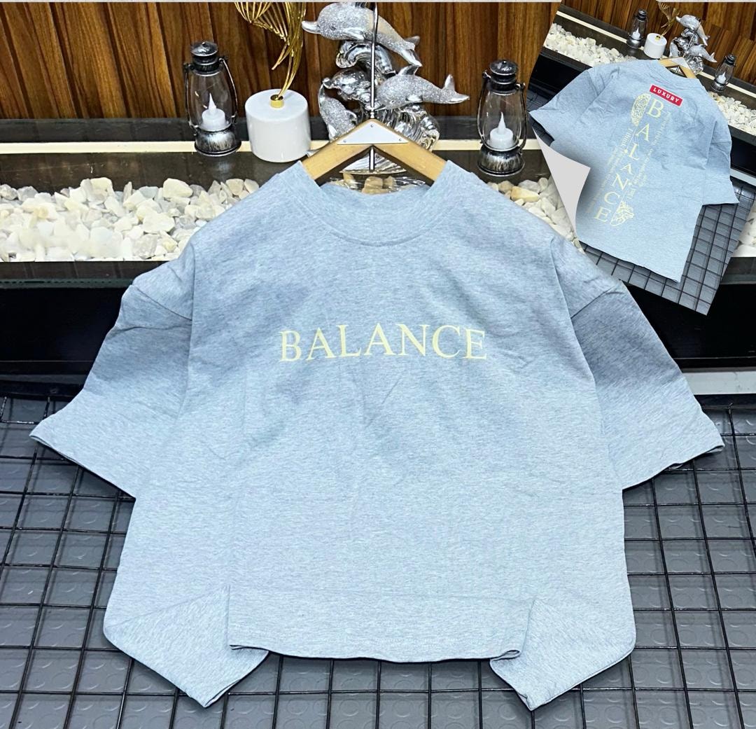 Gray oversized t-shirt on hanger with yellow 'BALANCE' text on chest