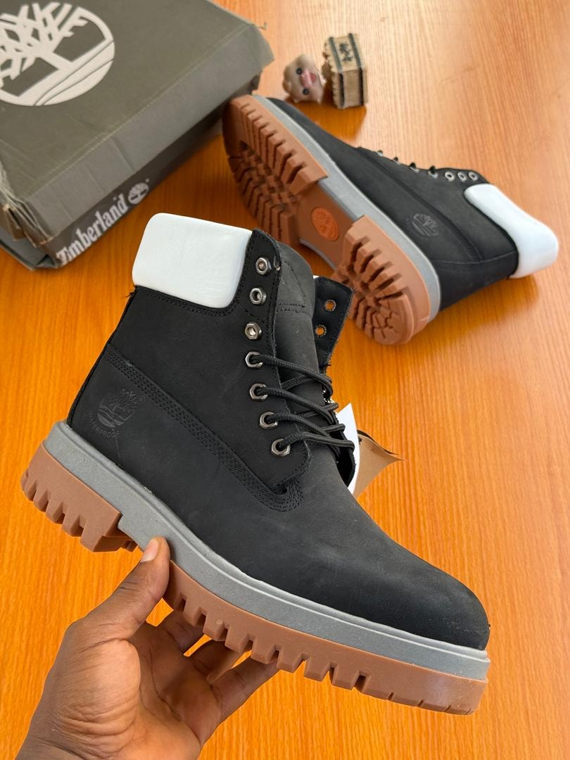 Black suede Timberland boot with white heel tab held in hand.