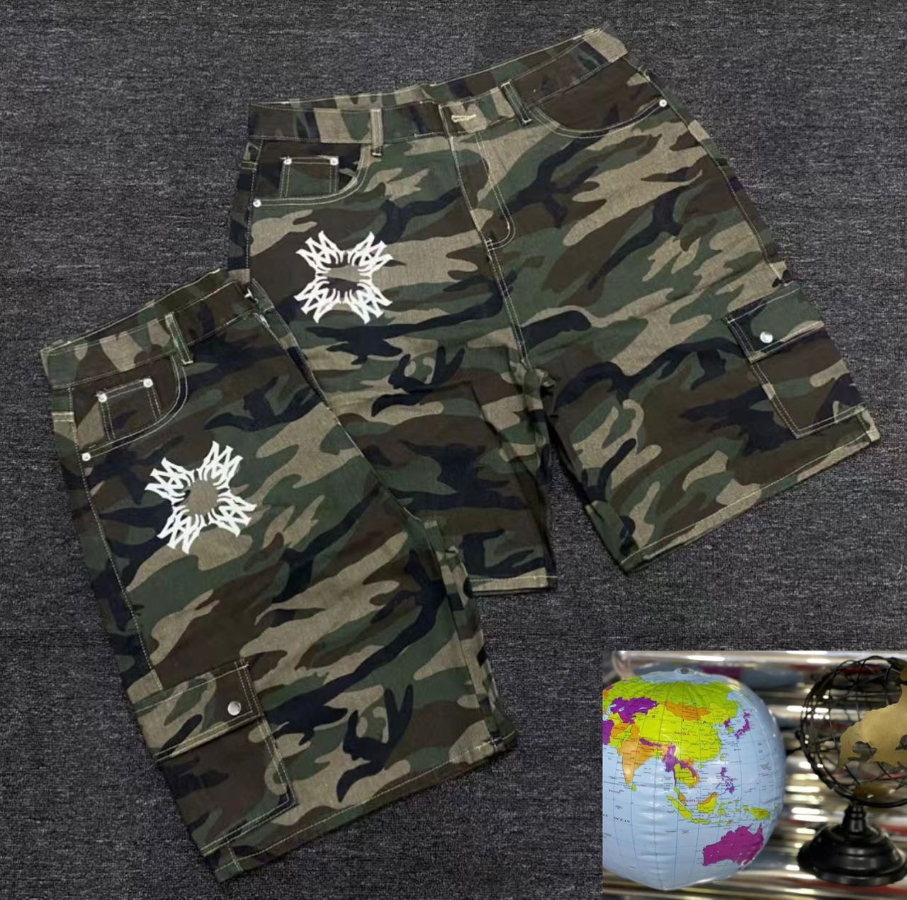 Baggy camouflage denim shorts with white graphic prints and cargo pockets.