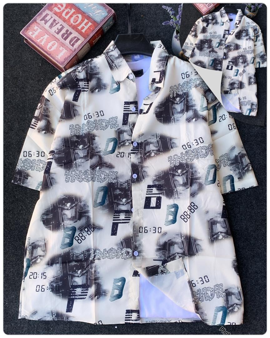 White short sleeve collared shirt with black white and teal digital abstract print beside books.