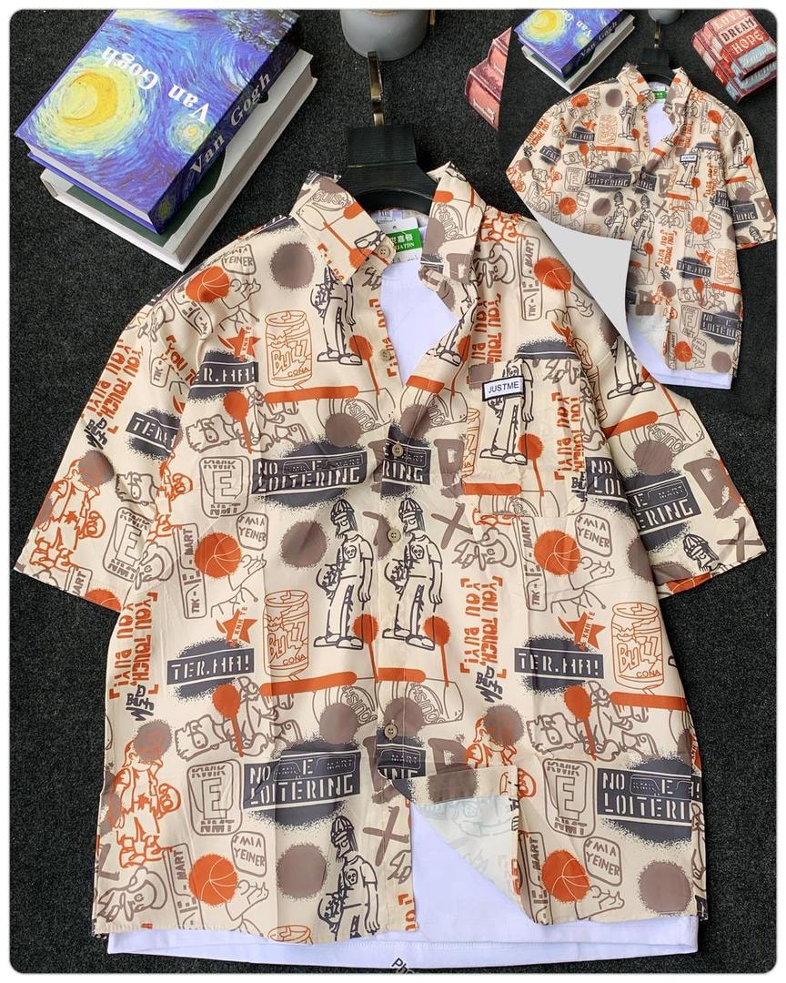 Beige short sleeve collared shirt with orange and brown graphic illustrations and text on dark surface.