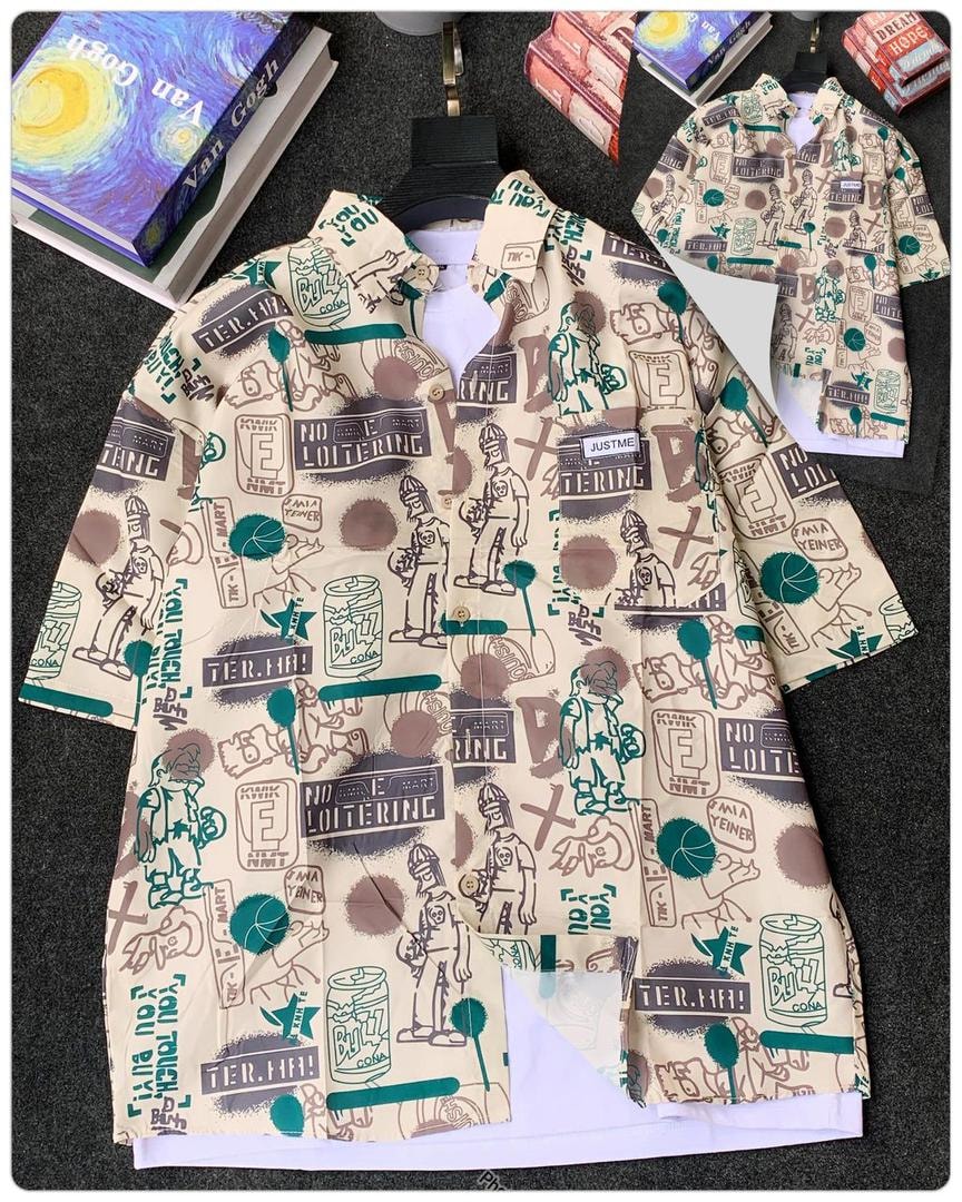 Beige short sleeve shirt with green and brown basketball illustration print beside books.