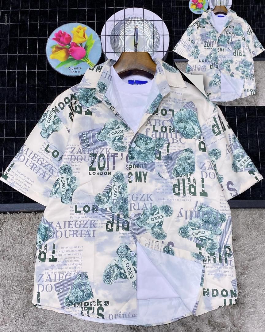 White short sleeve collared shirt with green newspaper collage print including ZOITS LONDON on textured surface.
