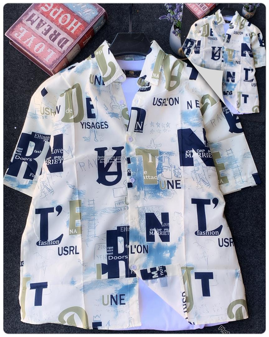 White short sleeve shirt with blue and green typographic collage print on dark background with books.