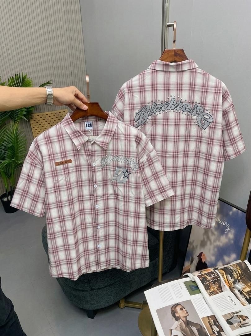 Pink plaid short sleeve button-up shirt held on wooden hanger showing front embroidery and back Blackrose design.