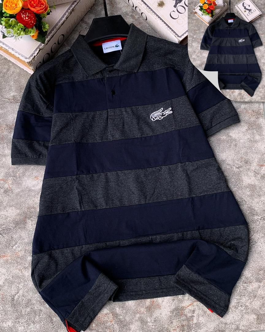 Lacoste striped polo shirt in navy and gray laid flat on textured surface.