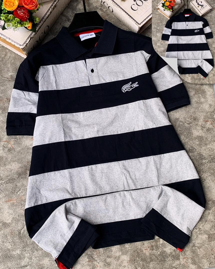 Lacoste striped polo shirt in navy and light gray laid flat on textured surface.