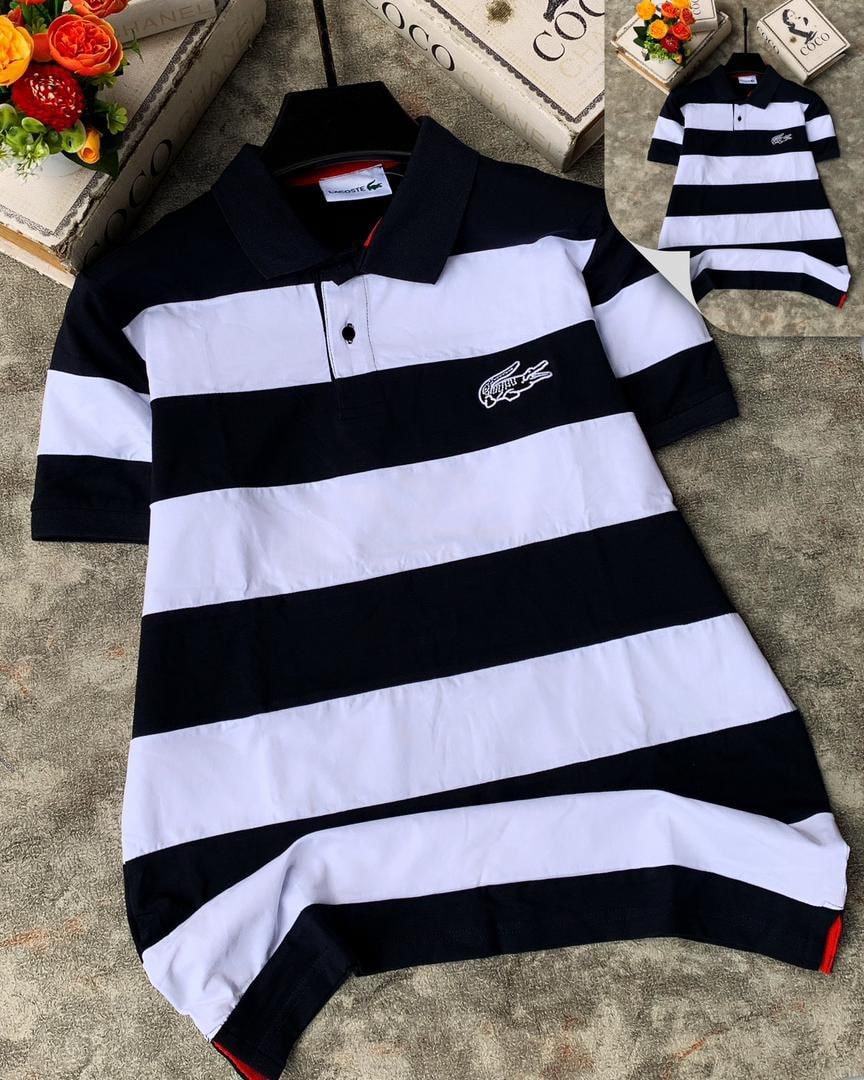 Lacoste striped polo shirt in black and white laid flat on textured surface.