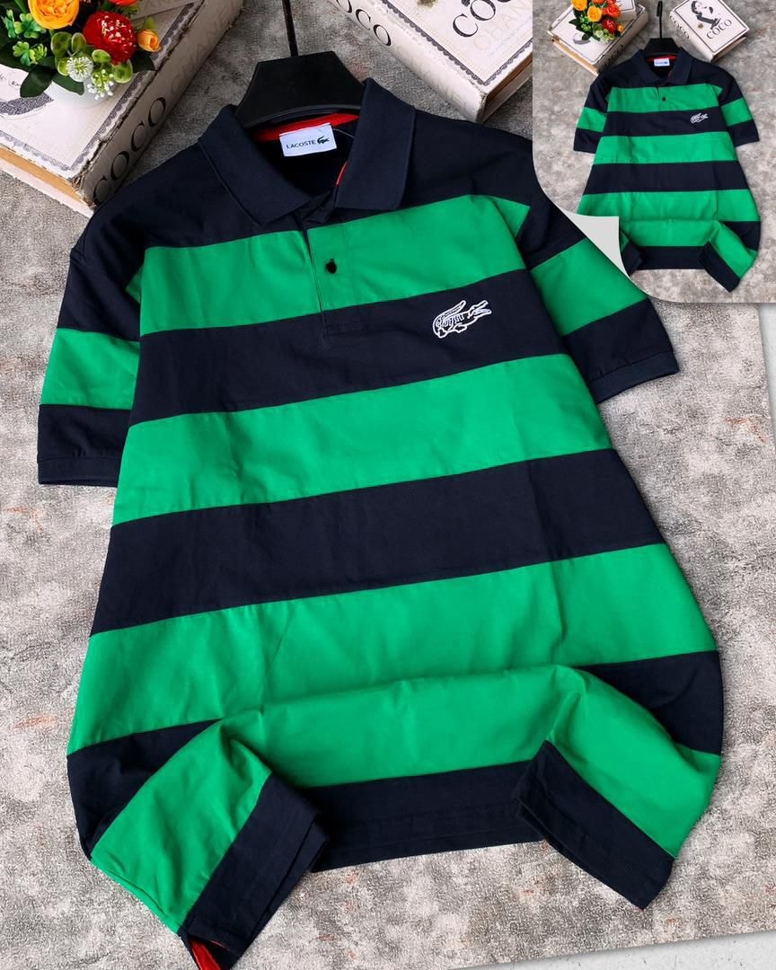 Lacoste striped polo shirt in navy and green laid flat on textured surface.