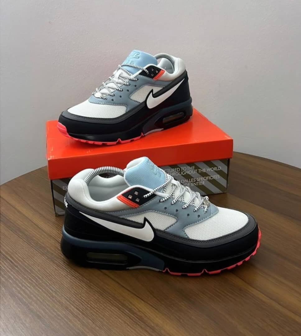 Grey, white, black, and blue Nike Air Max sneakers displayed on orange box.