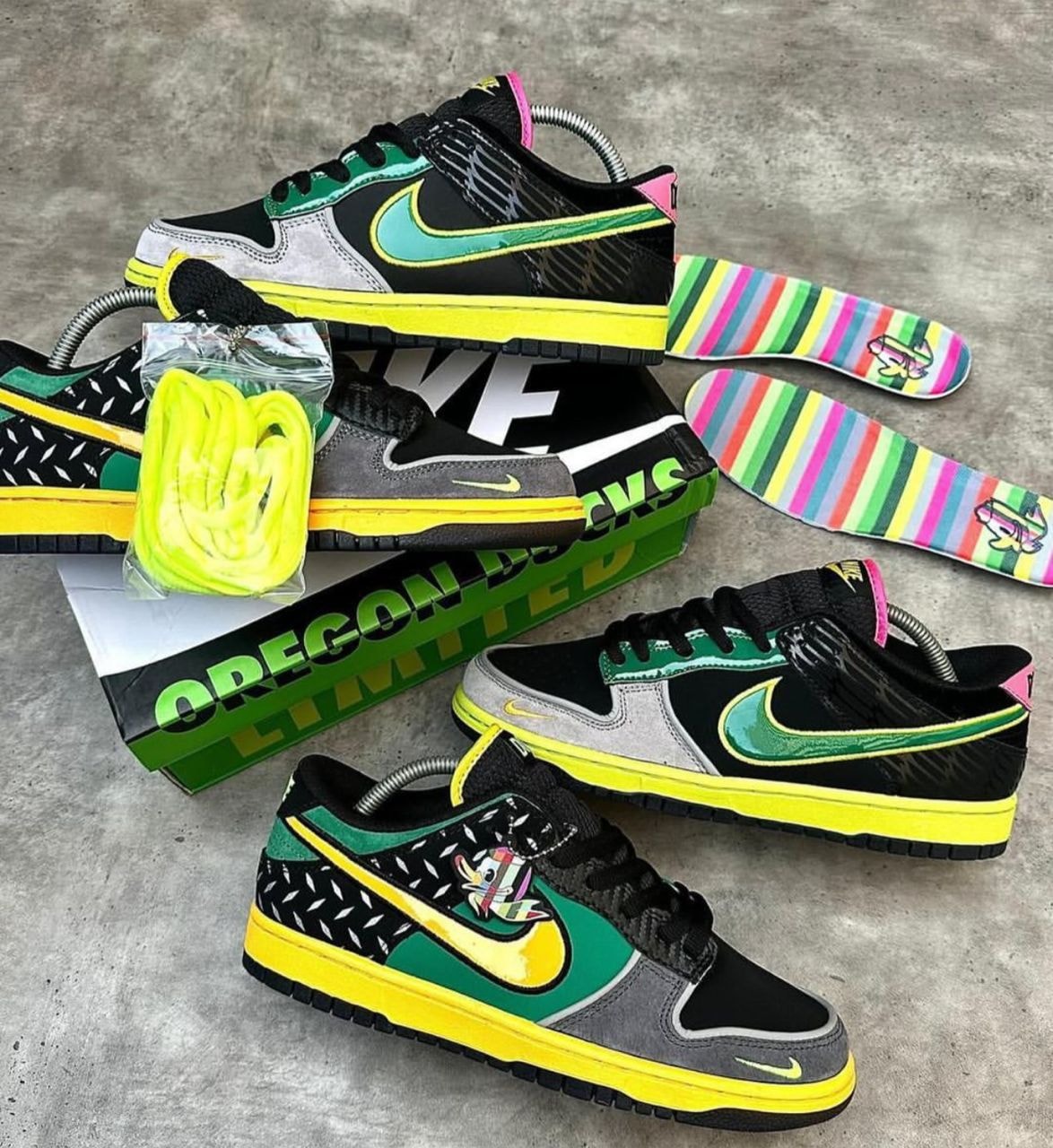 Black, green, yellow, and grey Nike Dunk Low sneakers with neon details and accessories.