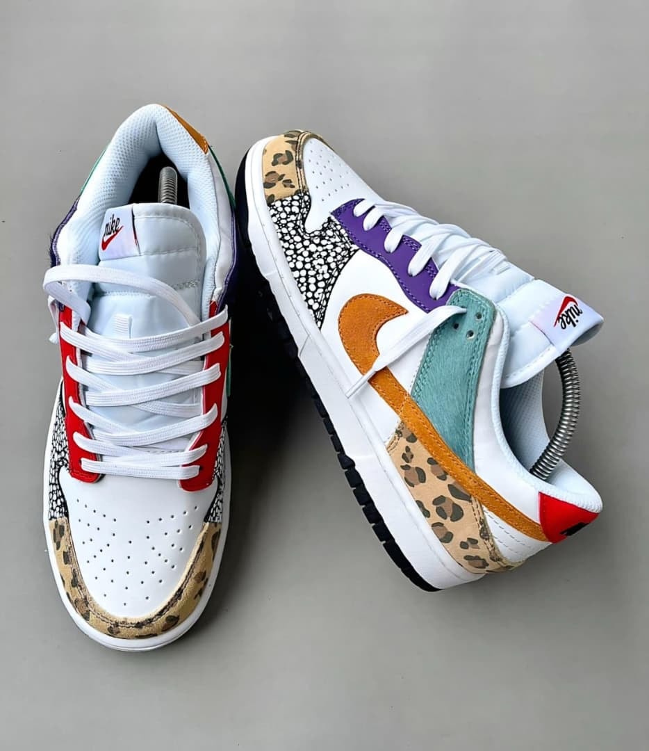 White Nike Dunk Low sneakers with leopard print, purple, red, and teal color blocking.