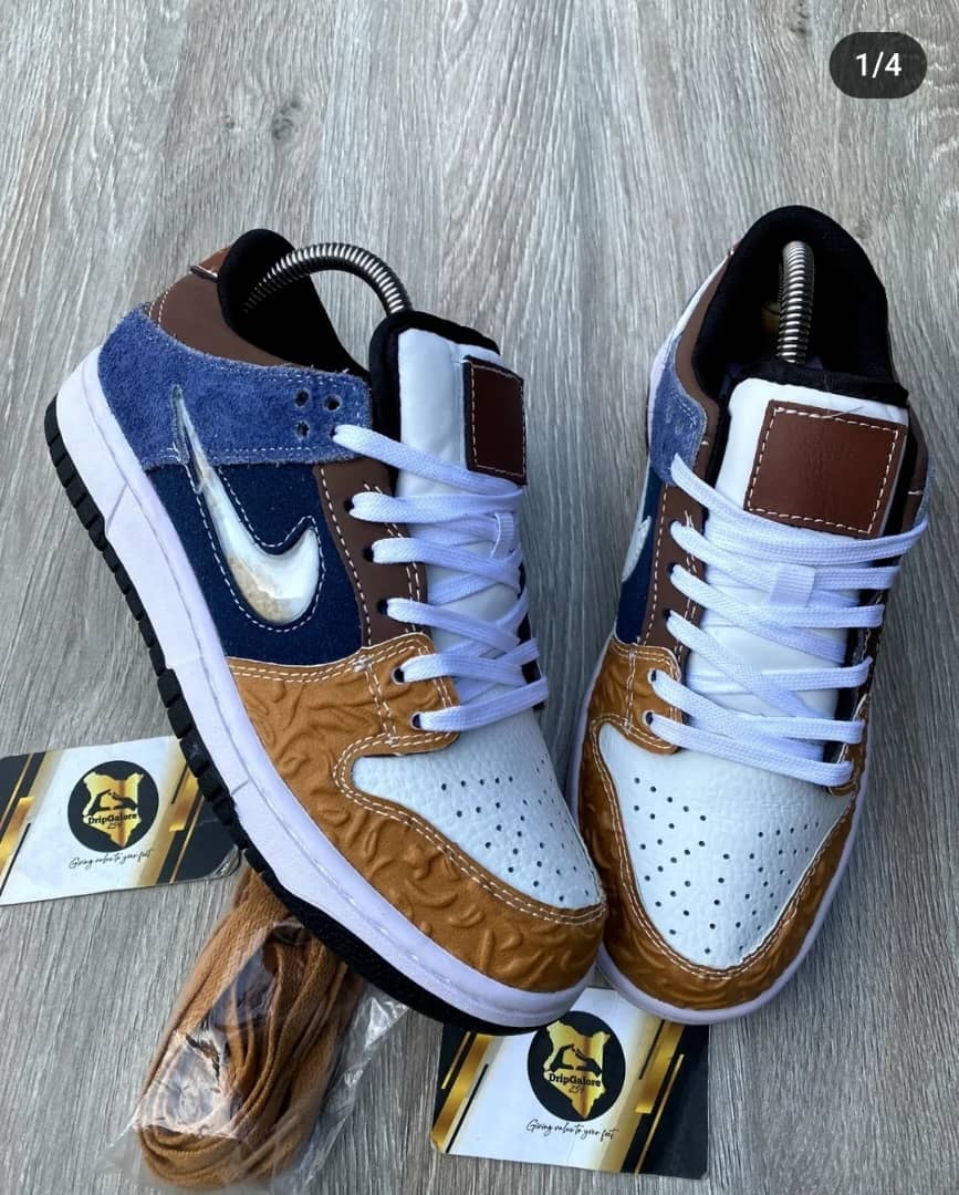 Brown, blue, and white Nike Dunk Low sneakers with textured toe box and branding card.