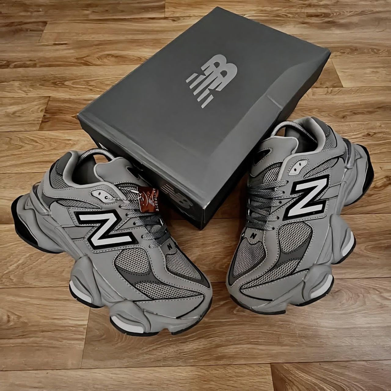 Gray New Balance 9060 sneakers on wooden floor with gray box.