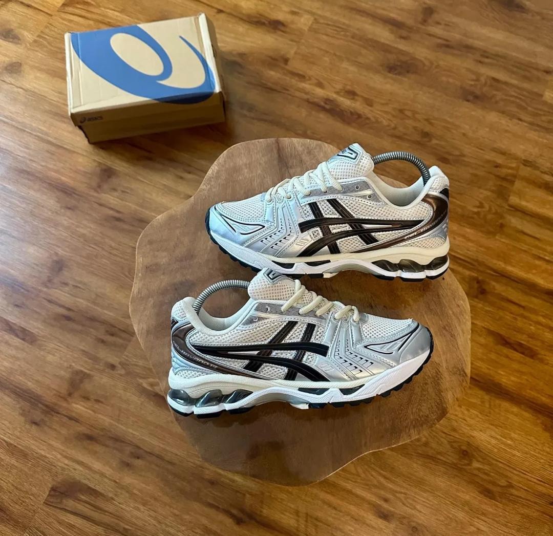 White silver and black Asics Gel sneakers on wooden surface with branded box.