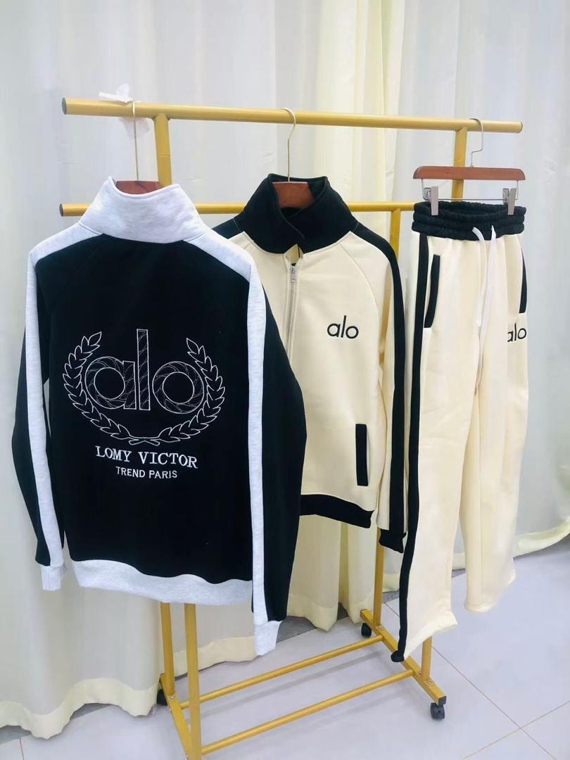 Track suit sets in black and cream colorways on yellow clothing rack showing front back and pants views.
