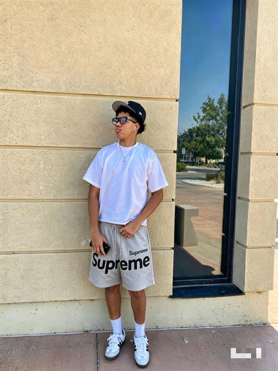 Model wearing gray Supreme logo fleece shorts with white tee, cap and sneakers.