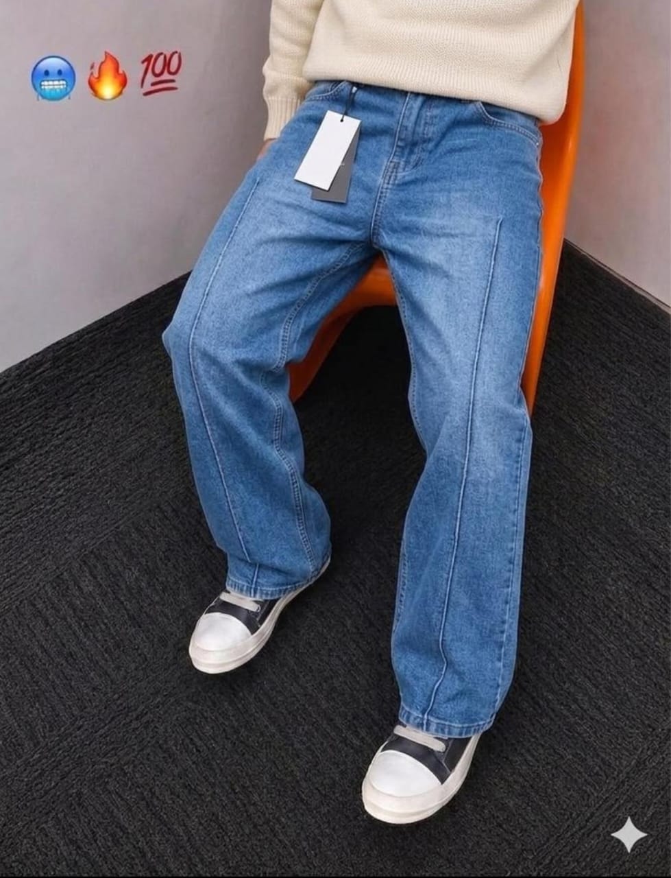 Person seated wearing light blue baggy jeans with white tag, on orange chair.