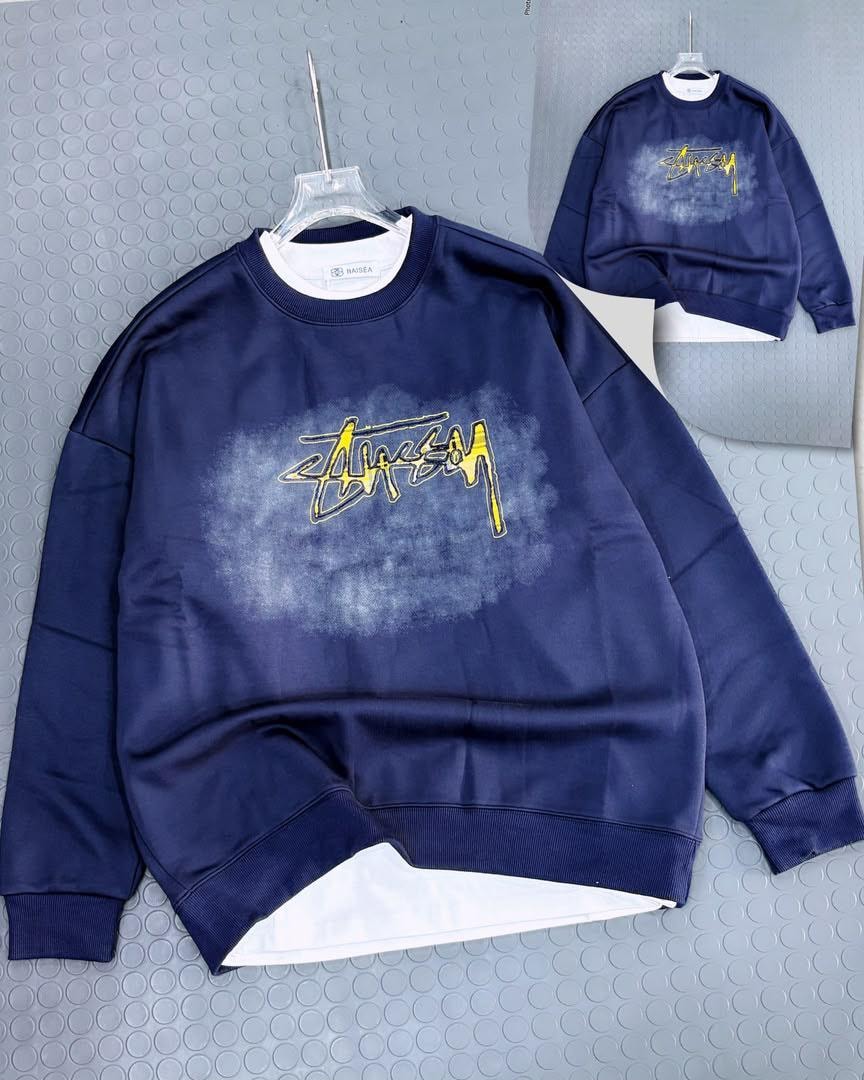 Navy blue Stussy sweatshirt with yellow script graphic on chest and back, shown on hanger.