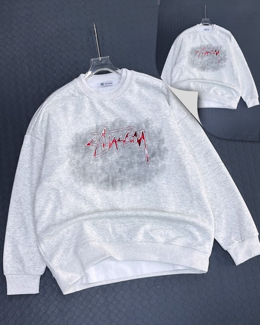 Light gray Stussy sweatshirt with red script graphic on chest and back, shown on hanger.