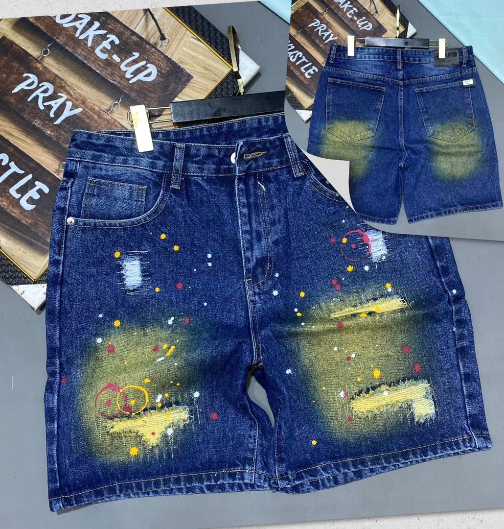 Front and back views of blue denim jorts with colorful paint splatter, rips and frayed hems.
