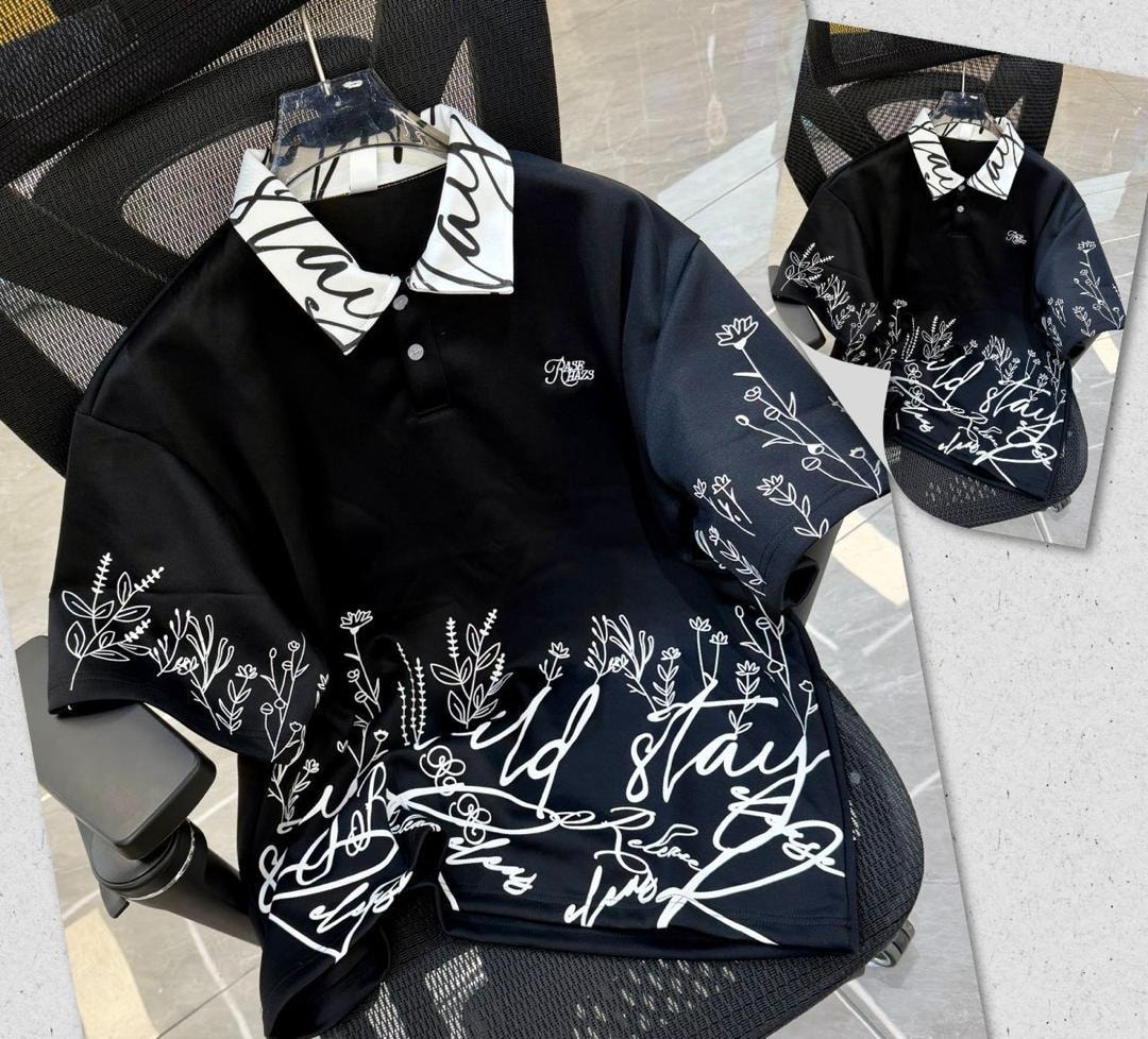Black printed polo shirt with white floral script designs and patterned collar.