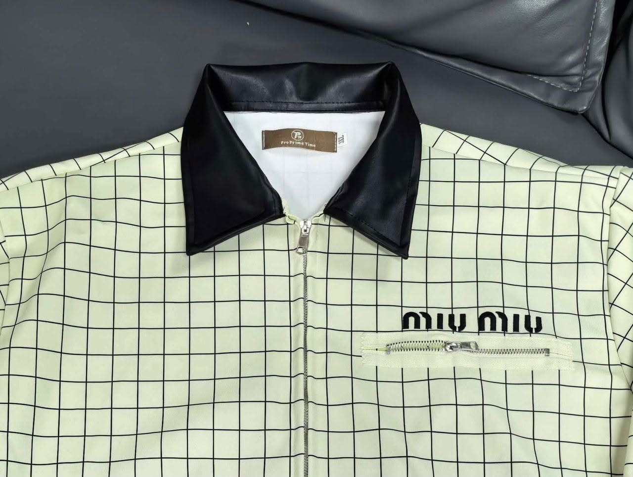 Close-up of cream grid jacket collar with black leather trim and miu miu branding.