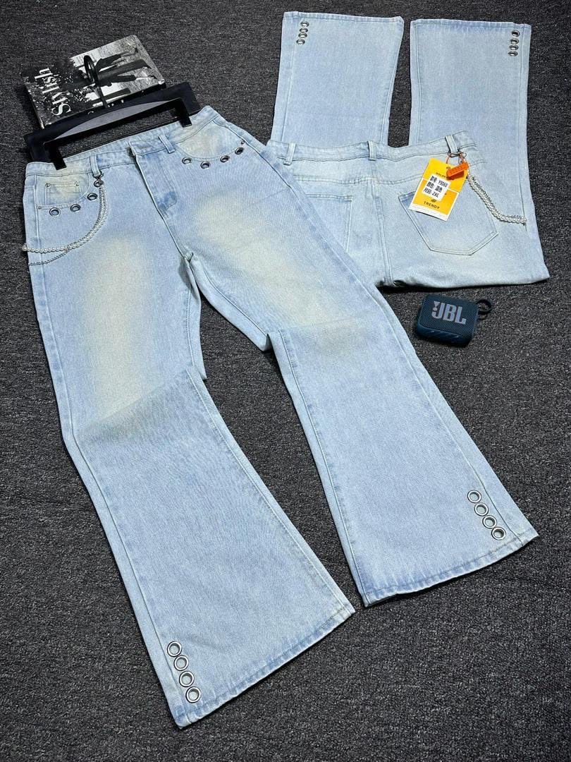Light blue baggy jeans laid flat showing front, back and eyelet details with chain accent.