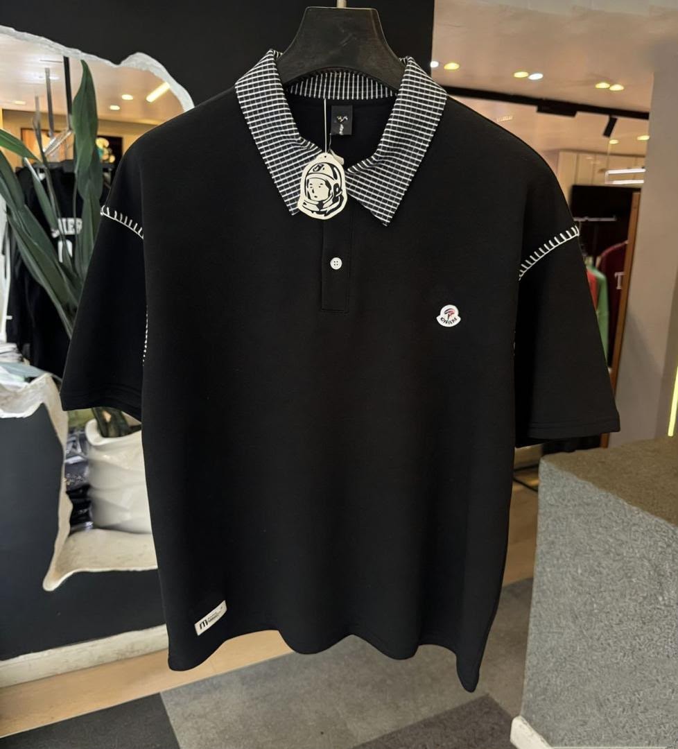 Black polo shirt displayed on mannequin, featuring checkered collar and chest logo.