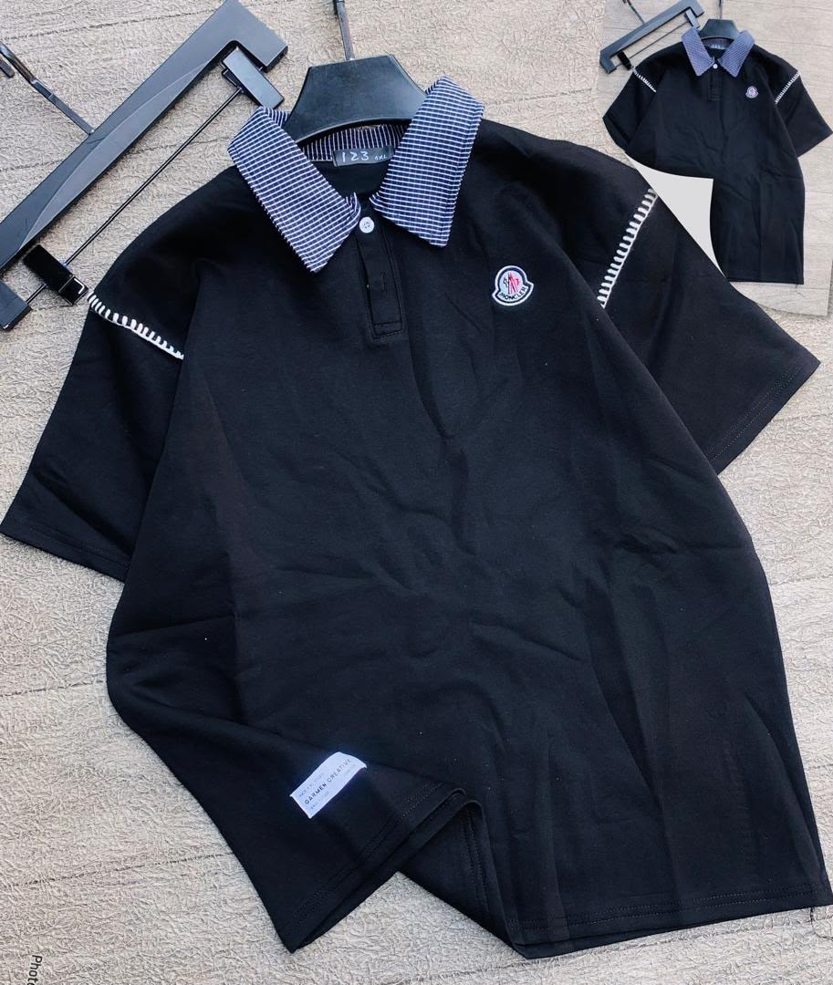 Black polo shirt with checkered collar laid flat, highlighting chest embroidery and shoulder stitching.