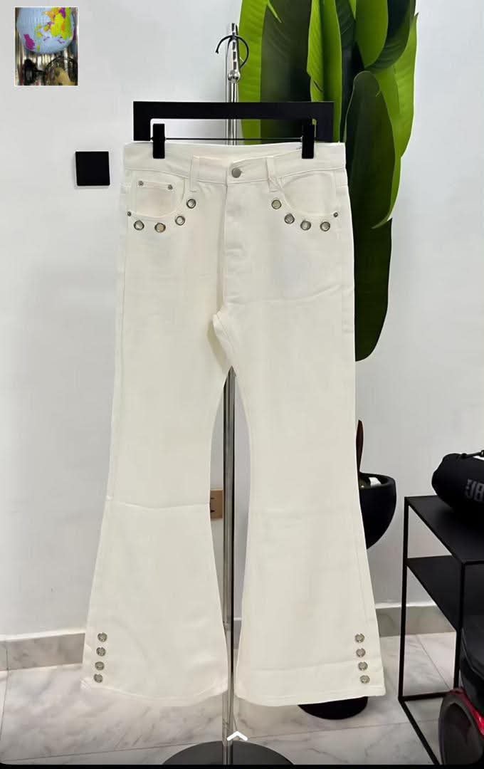 White flared jeans with silver studs on pockets and hems displayed on clothing stand.