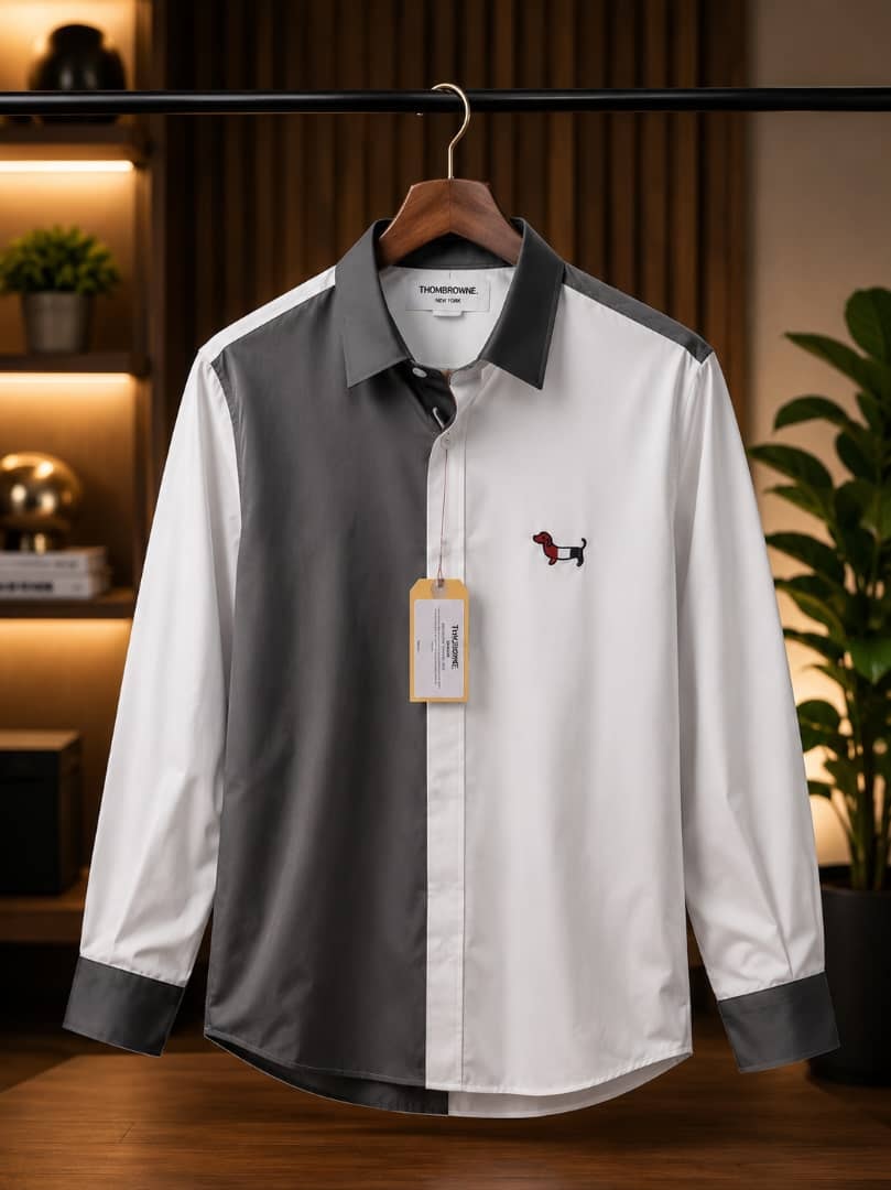 White and gray colorblock Thom Browne shirt with dachshund embroidery hanging on wooden hanger.