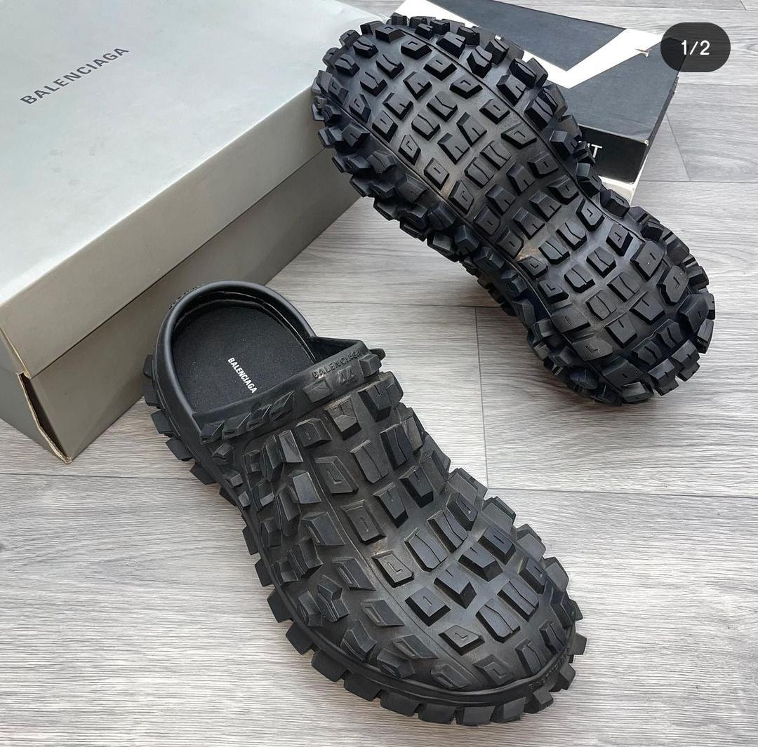 Black Balenciaga clog with heavy tread sole next to branded box.
