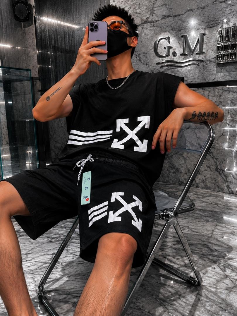 Man seated in solid black sleeveless top and shorts with white arrow graphics.