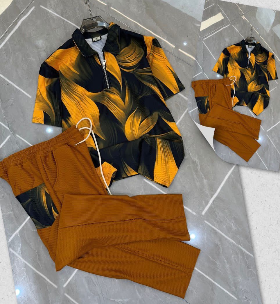 Yellow and black leaf print zip polo shirt with matching brown trousers on tiled floor.
