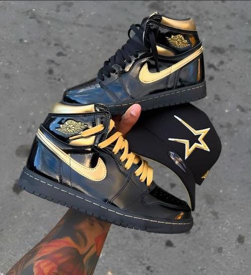 Black and gold Jordan 1 high sneakers held with black and gold cap.